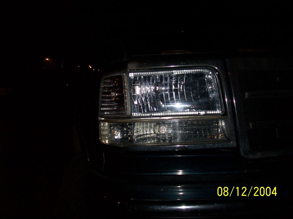 Clear-lens chrome headlight and turn signal on a dark truck photographed at night