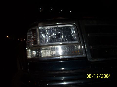 1994 Ford Bronco - Front view of a 1994 Ford Bronco's headlight and grille, captured at night.