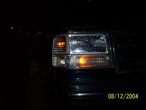 1994 Ford Bronco - The front corner of a black Ford F-150 truck is visible at night, with the headlight illuminated.