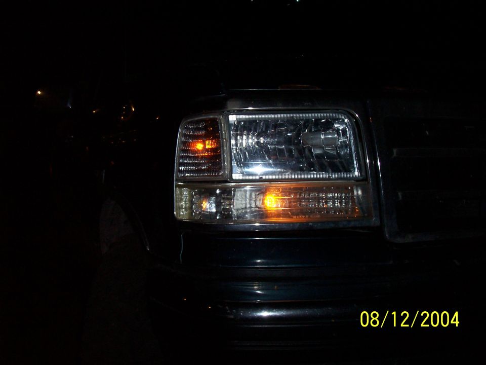 Clear-lens headlight with amber turn signals lit on a dark truck at night