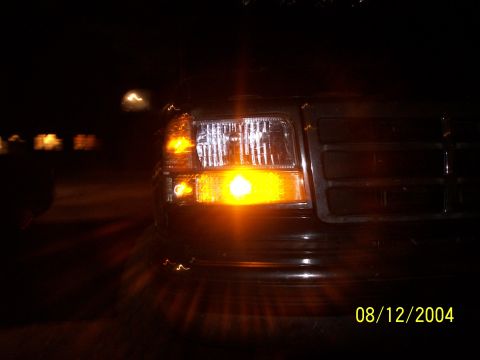 1994 Ford Bronco - Front corner view of a 1994 Ford Bronco at night, showing the headlight and grille.