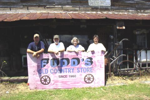 1995 Ford Bronco - Four people pose in front of Fudd's Old Country Store, holding a sign that reads "Fudd's Old Country Store Since 1960."