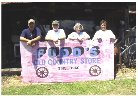 1995 Ford Bronco - Four people pose with a sign for Fudd's Old Country Store, established in 1960.