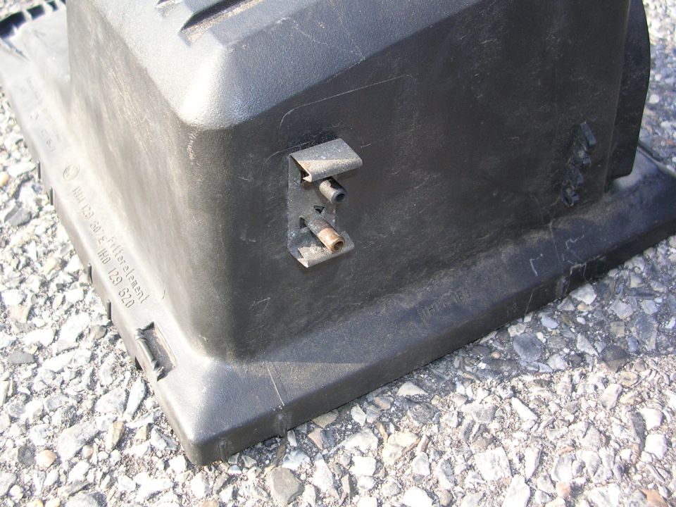 Black plastic air filter housing with metal bracket and visible text