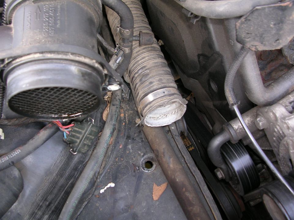Engine bay view showing air intake sensor, ribbed hose, and serpentine belt pulley