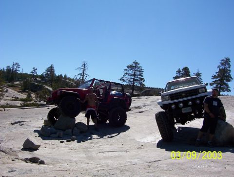 1976 Ford F-100 - Two modified off-road vehicles and two people pose on a rocky surface in a scenic outdoor location.