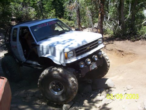 1976 Ford F-100 - This modified SUV navigates a challenging off-road course with large tires and auxiliary lights.