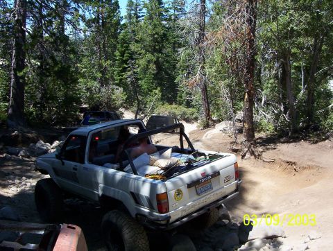 1976 Ford F-100 - A modified Toyota pickup truck navigates a rocky, wooded trail.