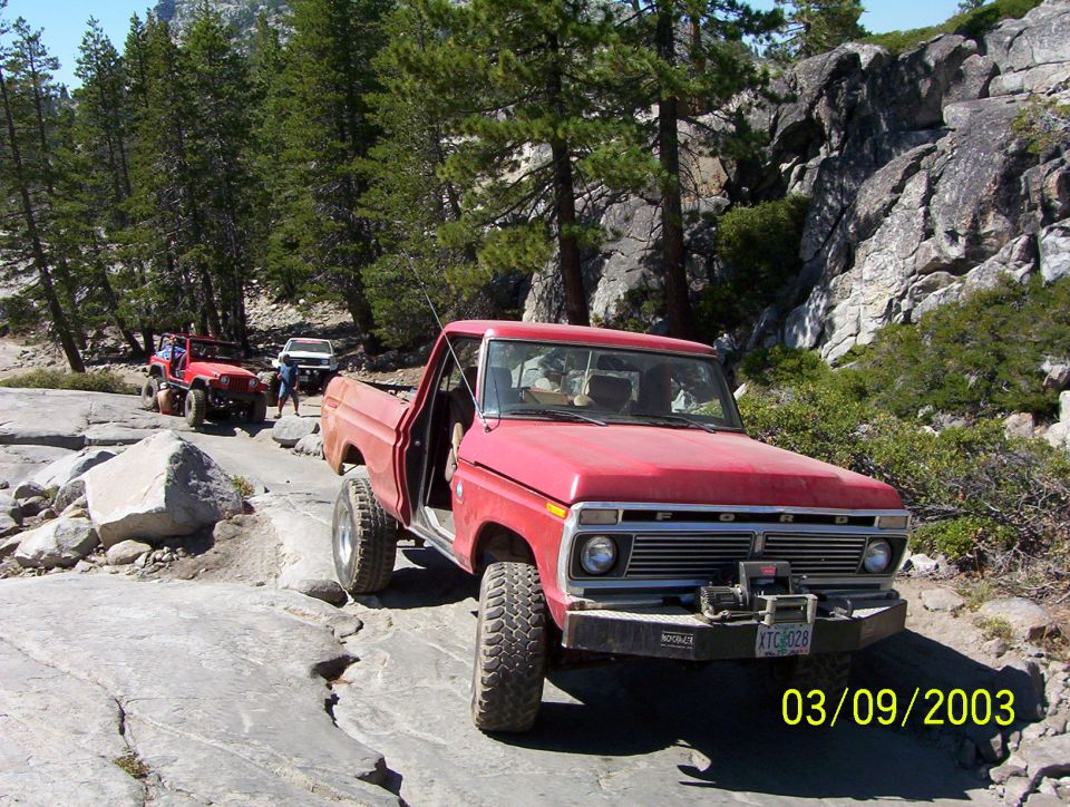 Red 1976 Ford F-100 on rocky terrain with winch and aftermarket bumper