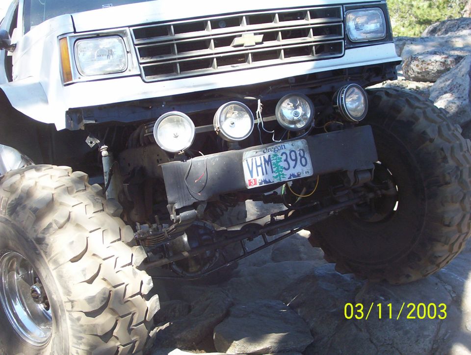 White truck with large tires and off-road lights, front view