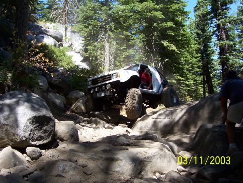 1976 Ford F-100 - A modified truck navigates a rocky trail in a wooded area.