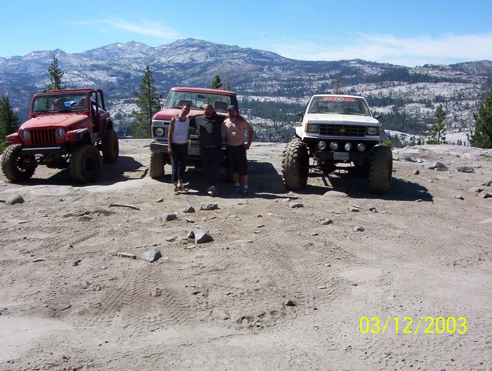 Red Jeep TJ, red Ford pickup and white Chevy 4x4 parked on granite mountain overlook