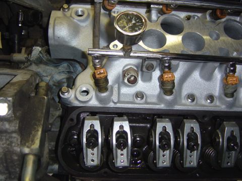 1993 Ford Bronco - Close-up of a V8 engine mid-assembly with the valve cover removed, showing the roller rocker arms and valve springs on the cylinder head. A…
