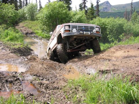 1985 Ford Bronco - Ford Bronco tackling a challenging muddy off-road course.