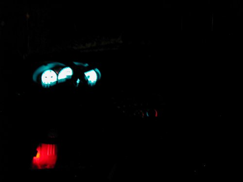 Dashboard gauges illuminated with blue light, red gear shifter below