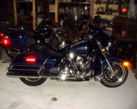 1985 Ford F-150 - Two motorcycles are parked inside a garage with shelves of items in the background.