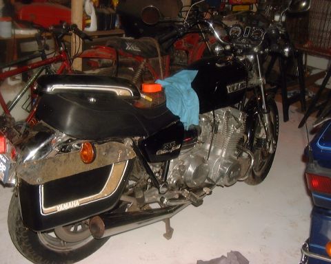 1985 Ford F-150 - A black Yamaha motorcycle with saddlebags is parked in a garage next to other items.