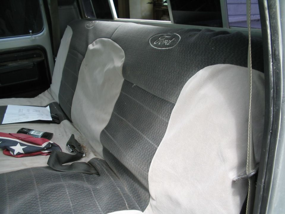Back seat of a Ford truck with a "Ford" logo on the headrest. A seatbelt is visible