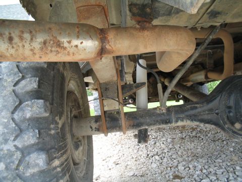 1979 Ford F-150 - Undercarriage view of a truck's rear axle and suspension system, showing leaf springs and a shock absorber.