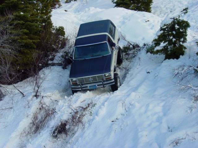 Dark blue full-size Bronco descending a snow-packed off-road trail