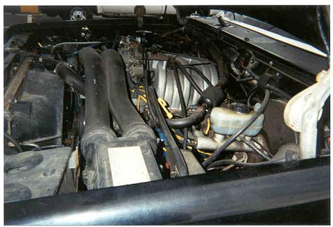 1989 Ford Bronco - The engine bay is visible, prominent black intake tubes and a brake fluid reservoir.