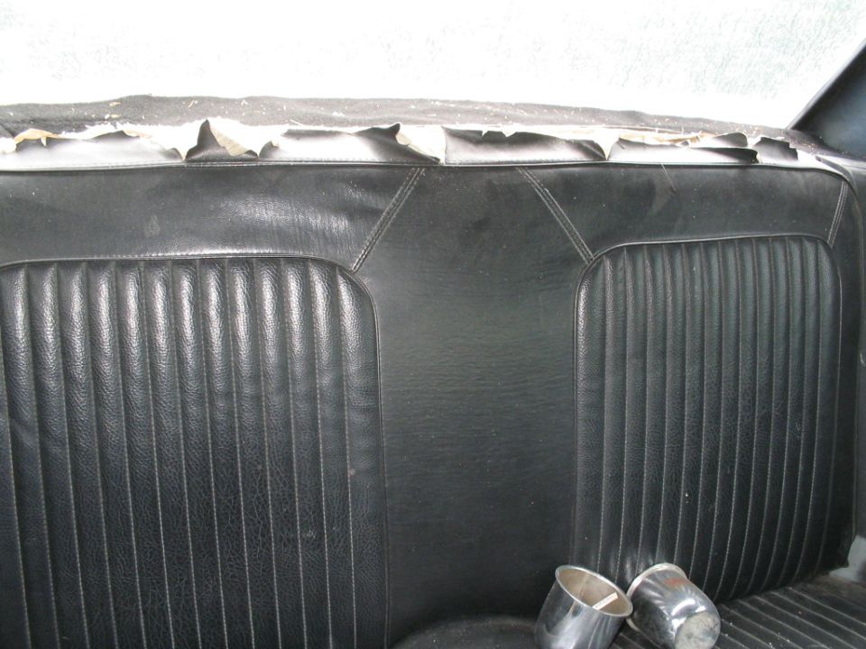 Back seat of a car with worn upholstery and chrome exhaust tips visible