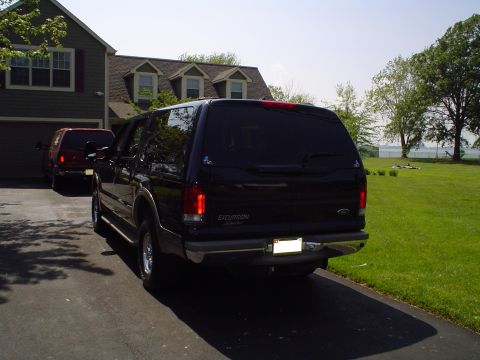 2000 Ford Excursion - Rear view of a dark 2000 Ford Excursion parked in a driveway, with a red SUV visible behind it.