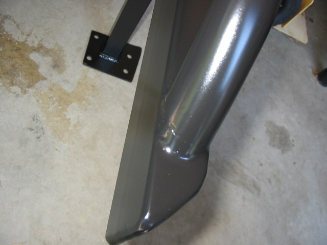 Metallic gray painted vehicle body panel on a stand over concrete floor