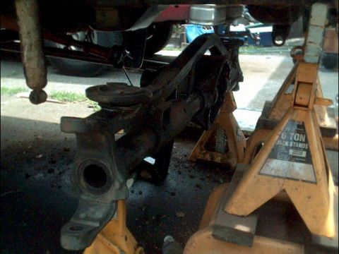 1978 Ford Bronco - Close-up view of a vehicle's front axle and suspension parts supported by yellow jack stands.