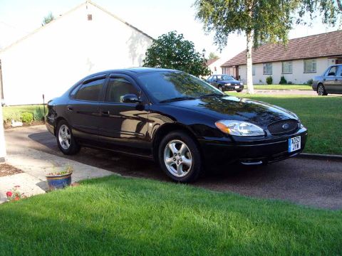 2004 Ford Taurus - A black 2004 Ford Taurus is parked in a residential driveway on a sunny day.