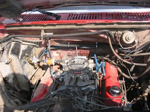 1985 Ford Bronco - Close-up of an engine bay, focusing on the carburetor and fuel system components.