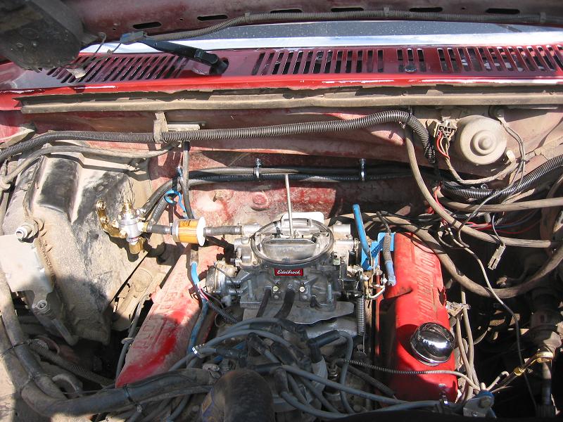 Edelbrock four-barrel carburetor on a V8 with red valve covers and blue plug wires