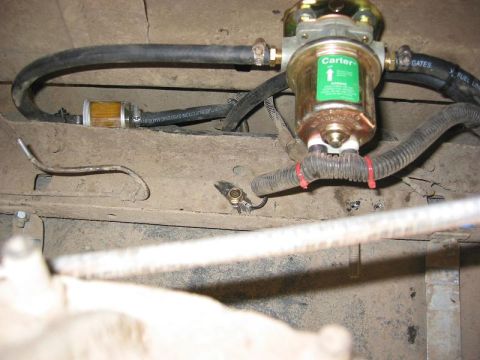 1985 Ford Bronco - Close-up of a Carter fuel filter and pump assembly, with a Gates fuel line, mounted beneath a vehicle.