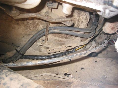 1985 Ford Bronco - Close-up of vehicle underbody showing fuel lines and wiring, with a SuperMotors watermark.