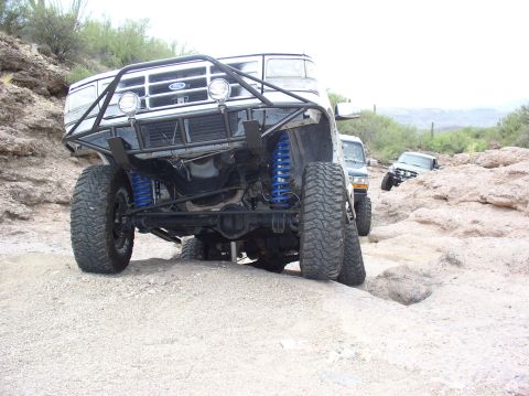 1993 Ford Bronco - Modified 1993 Ford Bronco navigating a rocky off-road trail with other vehicles present.