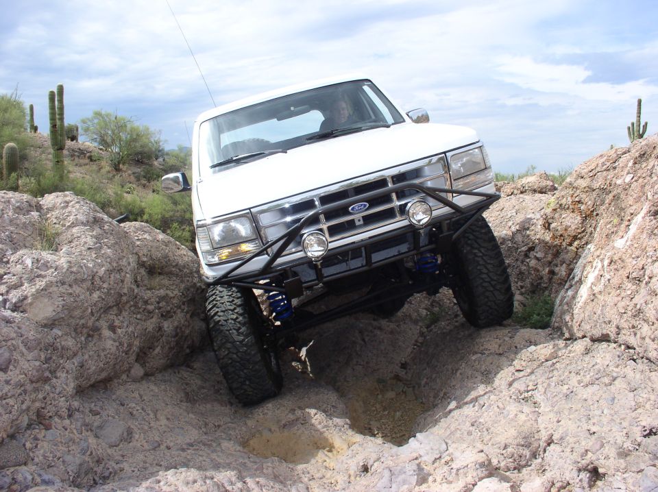White Ford Bronco with aftermarket bumper navigating rocky terrain