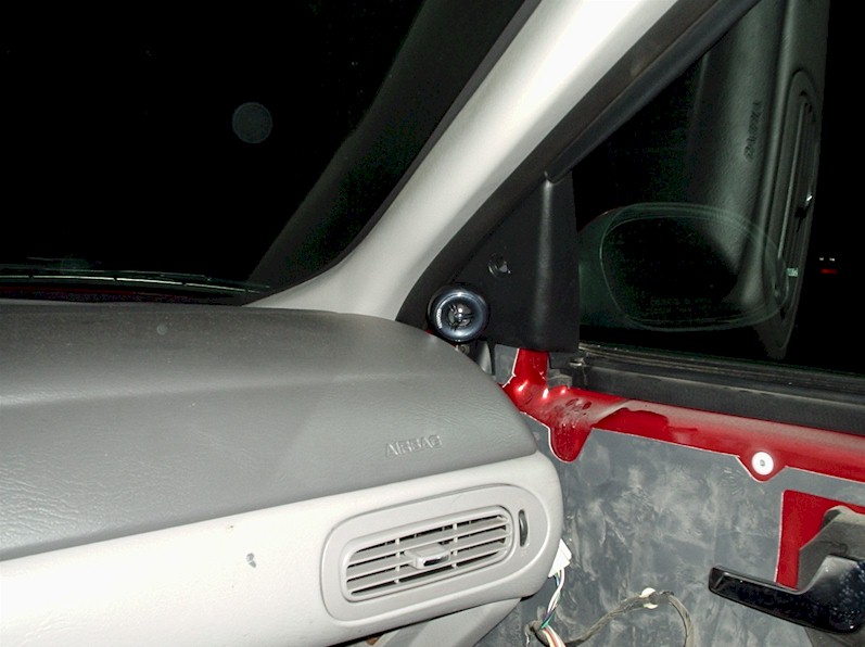 Gray dash and tweeter on sail panel of a red Ford Taurus with the door panel removed exposing the bare door