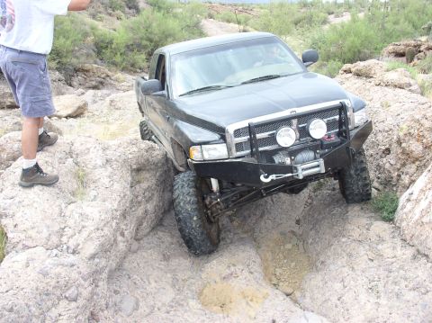1993 Ford Bronco - This black pickup truck, likely a Dodge Ram from the late 1990s, is shown tackling a challenging off-road course.