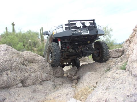 1993 Ford Bronco - Modified off-road vehicle tackling a challenging rocky trail in a desert environment.