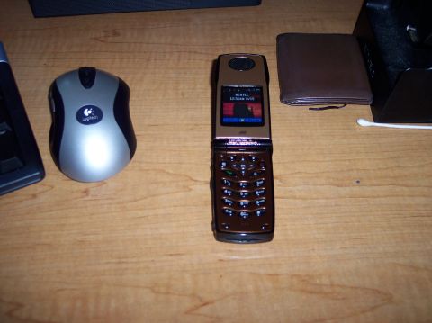 1990 Ford Bronco - A collection of desk items including a flip phone, mouse, and wallet are arranged on a wooden surface.