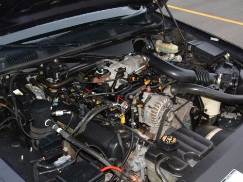 Engine bay showing V8 with alternator, black intake tube and brake master cylinder