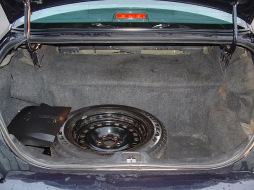 Open car trunk showing black steel spare wheel and tire