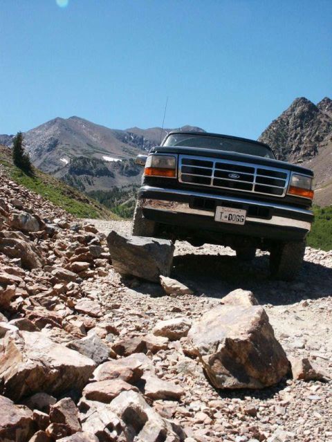 1996 Ford Bronco - Ford Bronco tackling a challenging off-road path in a mountainous landscape.