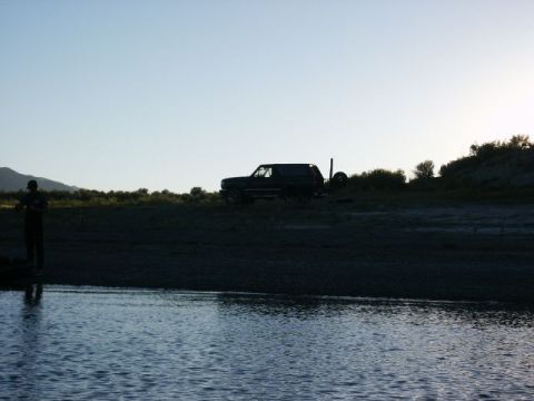 1996 Ford Bronco - A dark SUV, possibly a 1996 Ford Bronco, is parked on a hill overlooking a body of water.