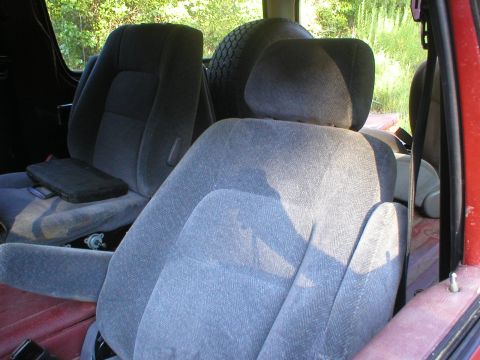 1986 Ford Bronco - The interior of a vehicle is shown, with a spare tire visible behind the seats.