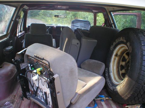 1986 Ford Bronco - The interior of a 1986 Ford Bronco shows removed seats and a spare tire, suggesting recent work or transport of parts.