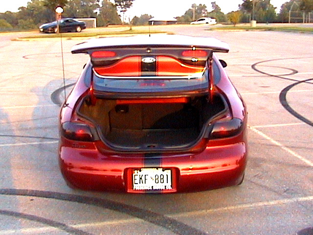 Rear of candy-red sedan with trunk open, blue stripes, rear wing and EKF 881 plate