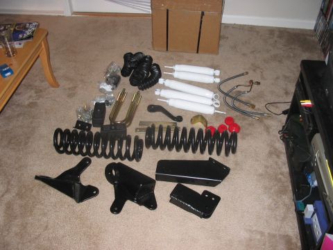 1988 Ford Bronco - Various suspension components, likely for a 4-inch lift kit, are spread out on the floor.