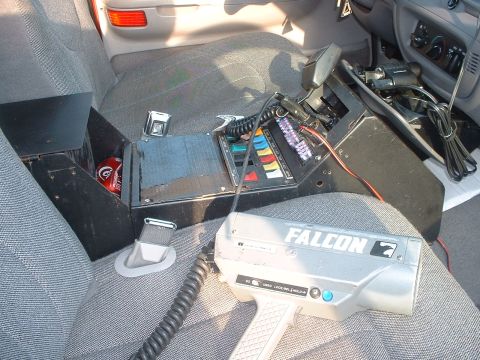 1999 Ford Crown Victoria - The interior of a police vehicle is visible, equipped with a radar gun and a control console.