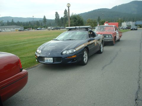 1999 Ford Crown Victoria - Police car with light bar parked on asphalt, another car behind it.